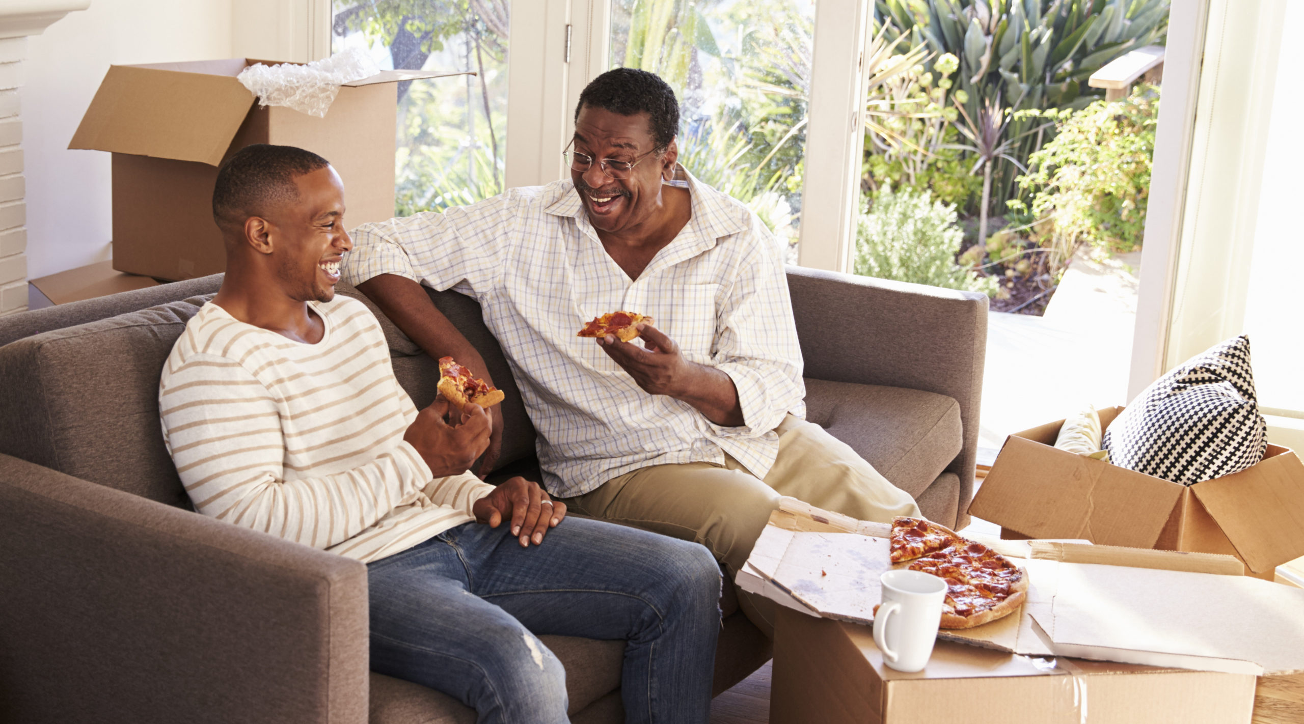Father And Adult Son Take A Break With Pizza On Moving Day